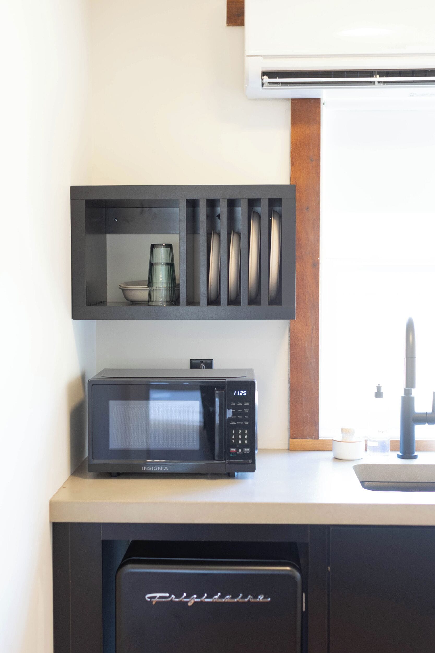 Een keuken met een magnetron, een koffiezetapparaat en een spoelbak.