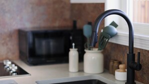 A kitchen with a black faucet, a microwave, and a white countertop. - The Stranger Lodge (Sisters)