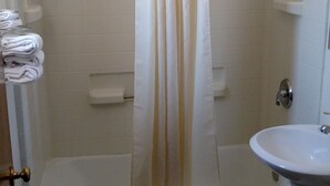 A bathroom with a bathtub, a shower curtain, a toilet, and a sink. - Budget INN (Durango)