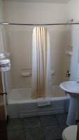 Un baño con bañera, cortina de ducha, inodoro y lavamanos.