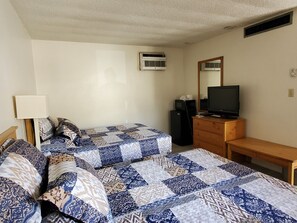 Une chambre d’hôtel avec deux lits, une télévision, une commode et un appareil de climatisation.