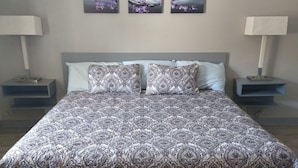 A bedroom with a large bed, two nightstands, and three wall-mounted paintings. - Budget INN (Durango)