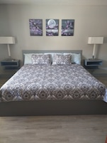 Un dormitorio con una cama grande, dos mesitas de noche y tres cuadros colgados en la pared.
