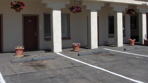 A row of single-story buildings with numbered parking spaces and potted plants. - Budget INN (Durango)