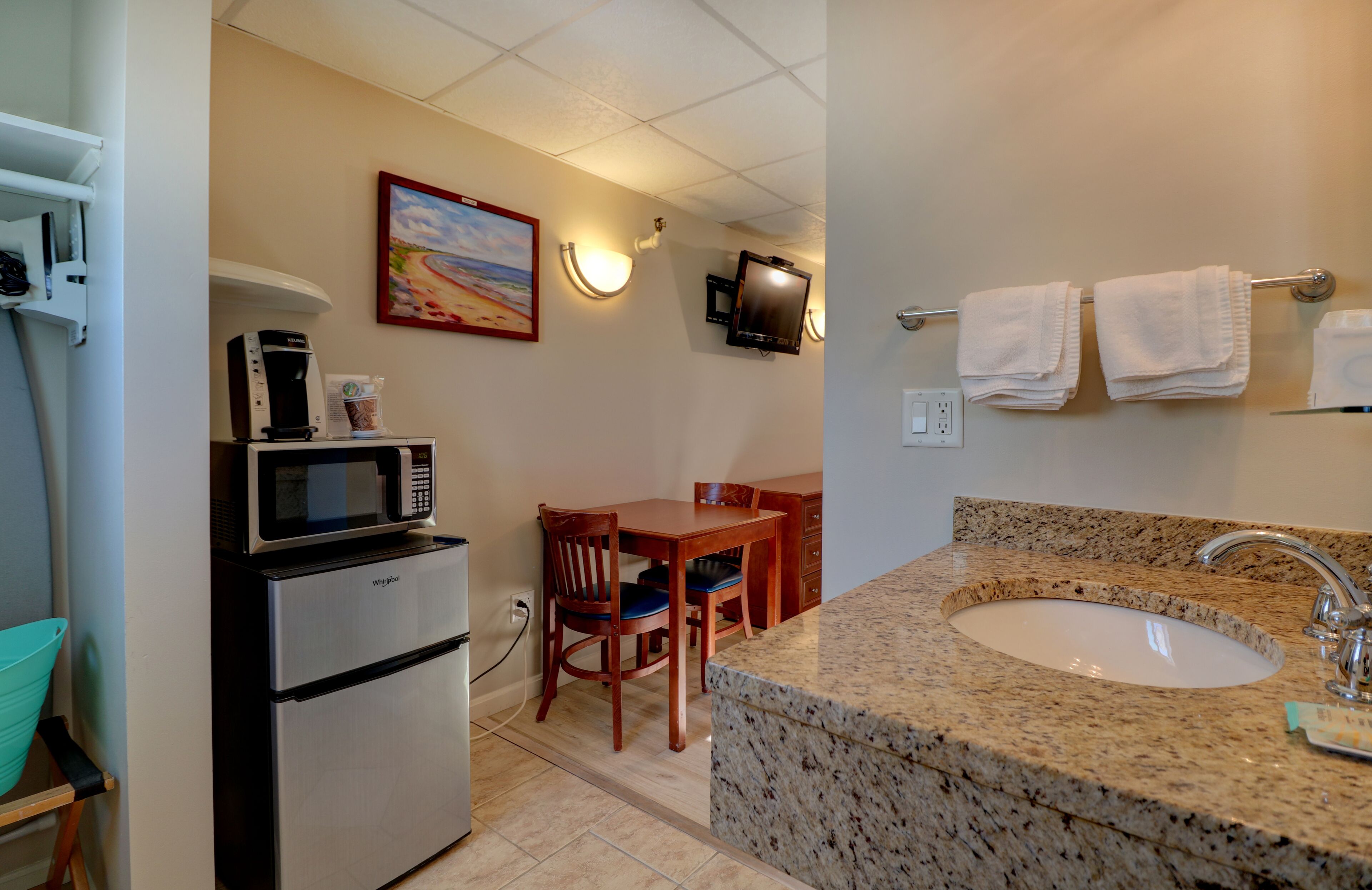 A compact kitchen with a microwave, coffee maker, and a dining area with a table and chairs.