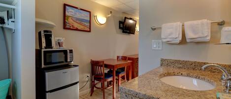A compact kitchen with a microwave, coffee maker, and a dining area with a table and chairs.
