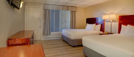 Quarto de hotel com duas camas, uma escrivaninha de madeira, televisão e janela com cortinas.
