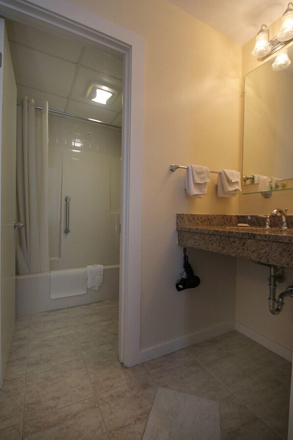 A bathroom with a shower, a sink with a mirror, and a towel rack. - Atlantic Oceanfront Hotel (Wells)
