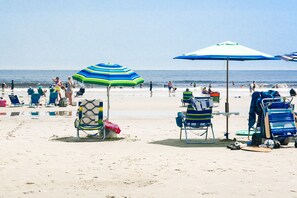 A beach with rows of beach chairs and umbrellas, a clear sky, and the ocean in the background. - Atlantic Oceanfront Hotel (Wells)