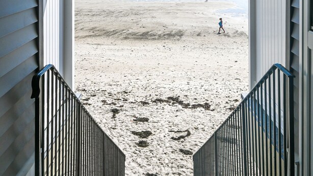 A covered walkway leading to a beach with a view of the ocean.