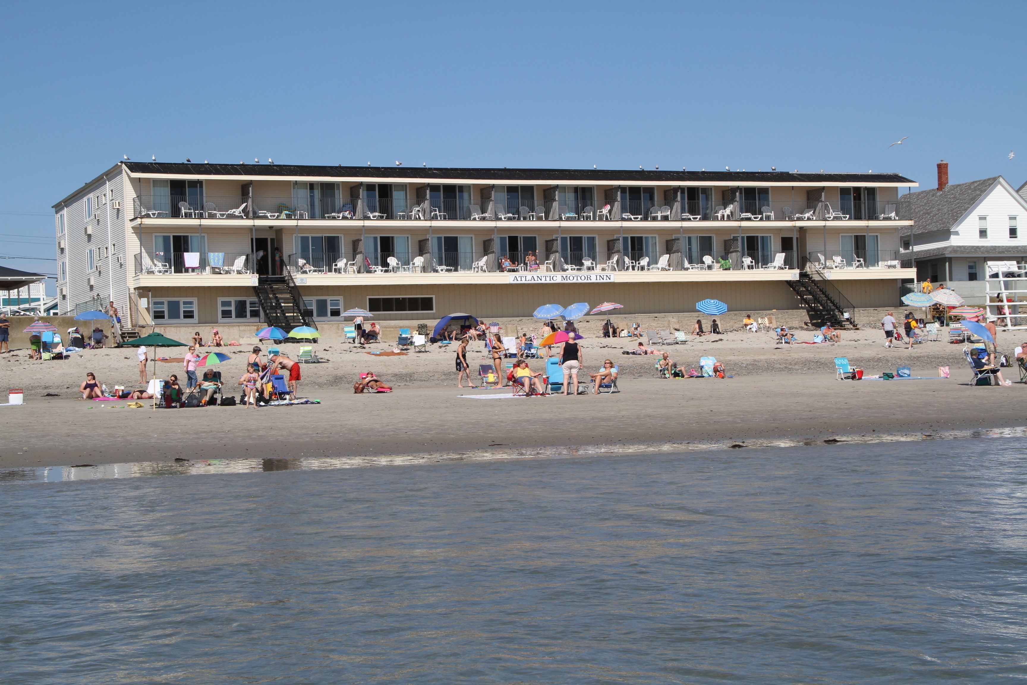 A beachfront hotel with multiple balconies, beach chairs, and umbrellas.