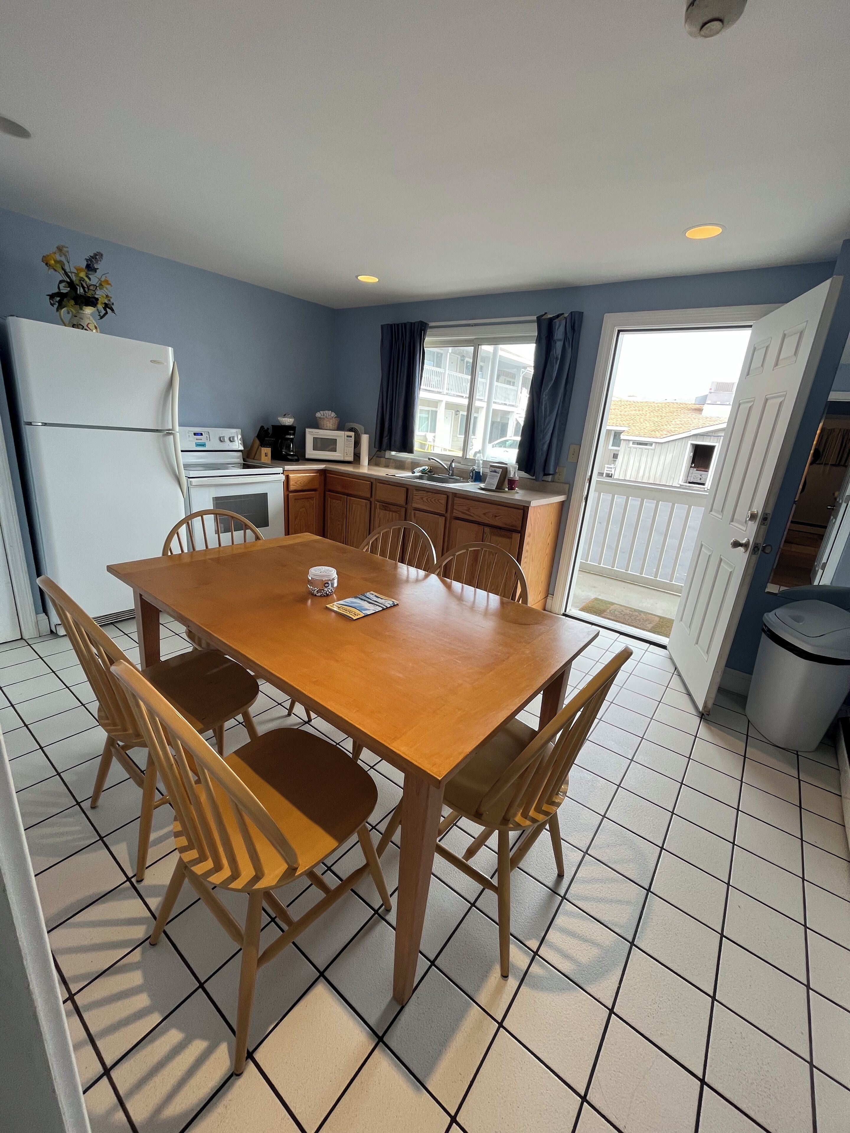 A compact kitchen with a dining table and chairs, a refrigerator, microwave, and a stove.