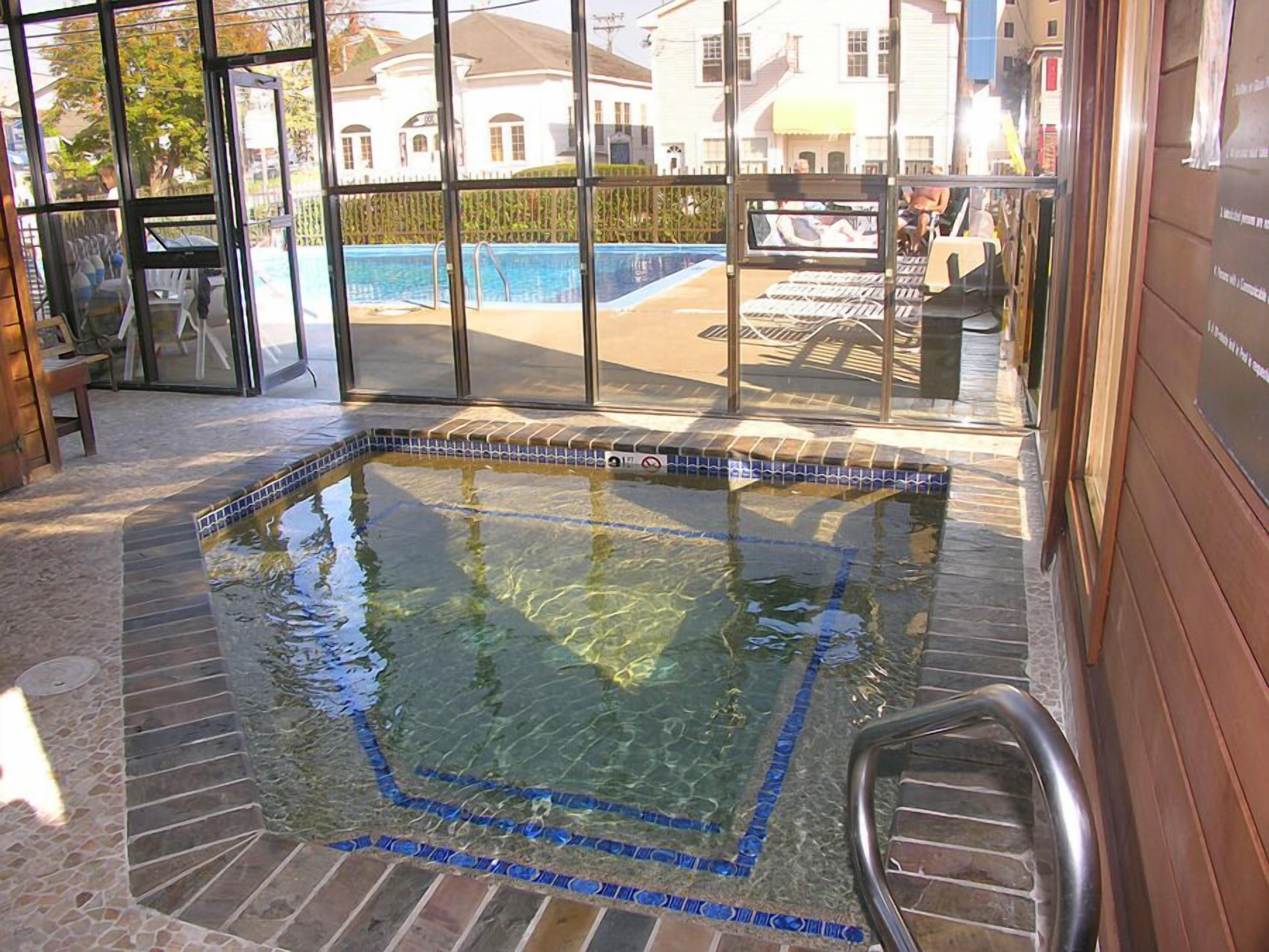 Ein Hallenschwimmbad mit klarem Wasser, umgeben von einer gefliesten Terrasse und einer Holzwand.
