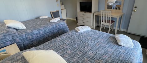 A hotel room with two beds, a desk, a chair, a television, and a mirror.
