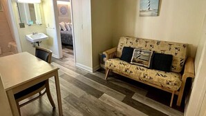 Ein gemütlicher, kleiner Wohnbereich mit einer Couch, einem Tisch und einem Waschbecken.