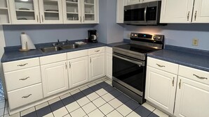 Eine Küche mit weißen Schränken, einem schwarzen Backofen und einer blauen Arbeitsplatte.