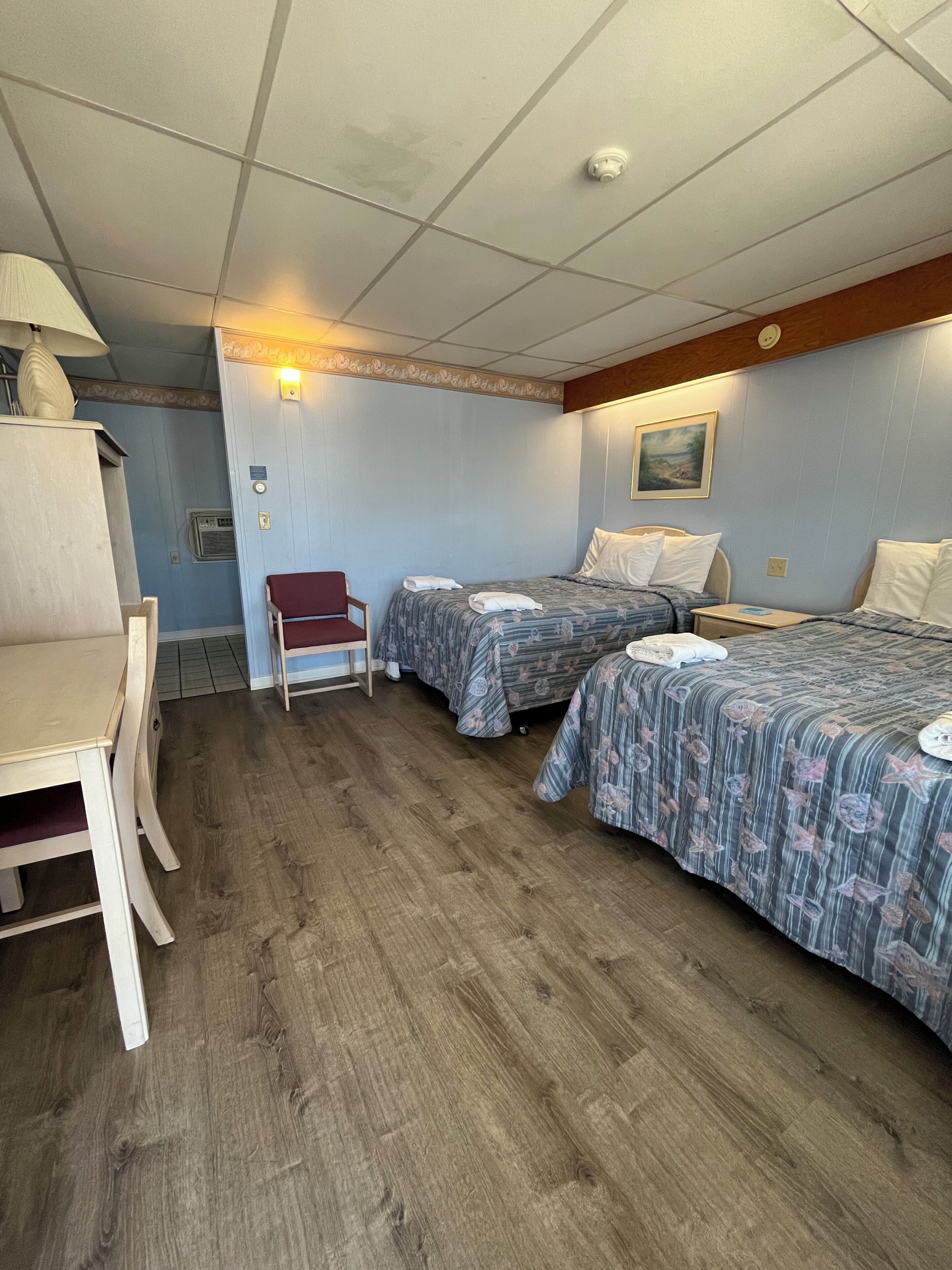 A motel room with two beds, a desk, and a chair.