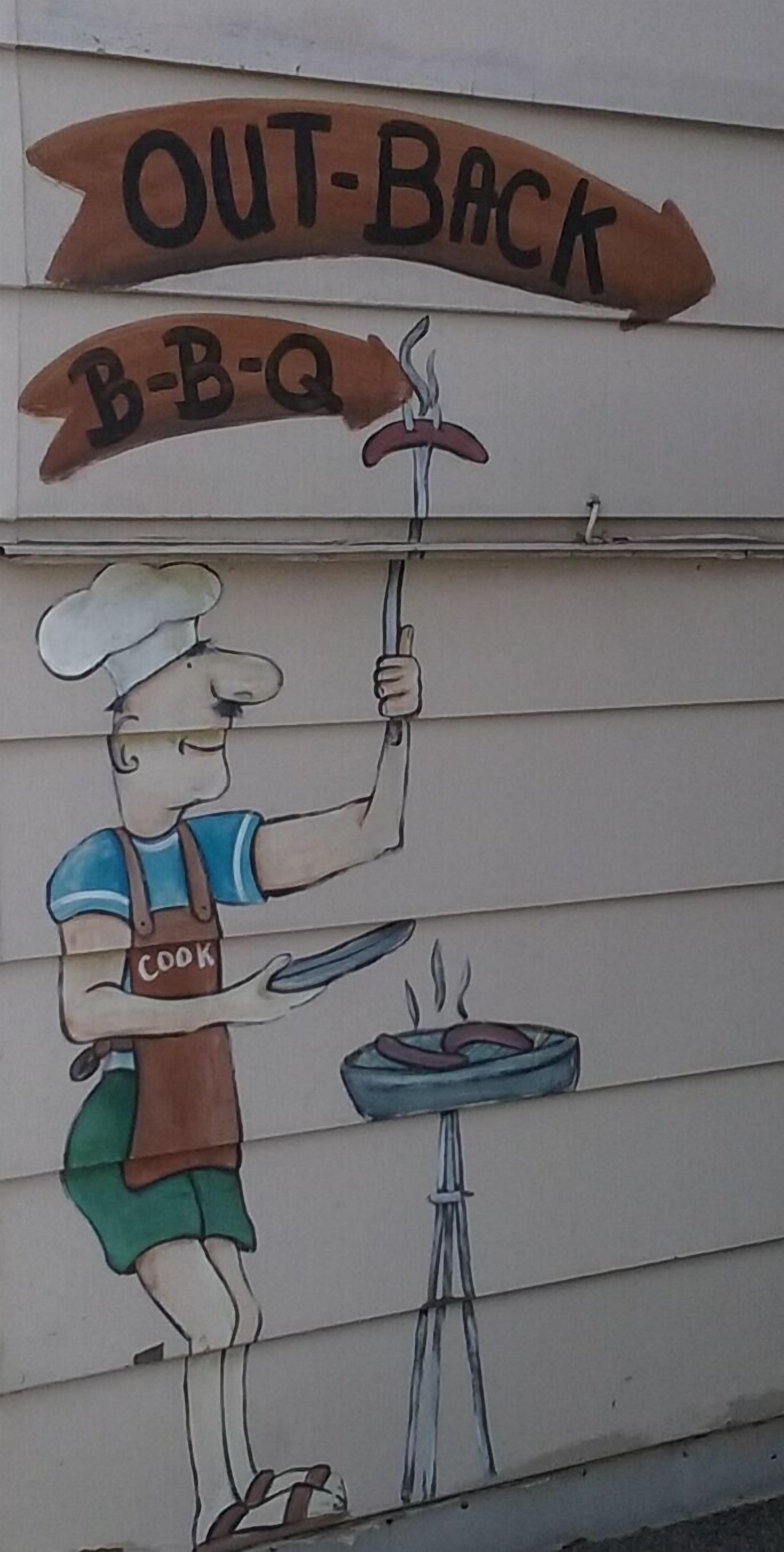 A mural of a chef holding a grill with a sign above reading "OUT-Back B-B-Q".