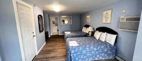 A bedroom with two beds, a hallway, and a door.