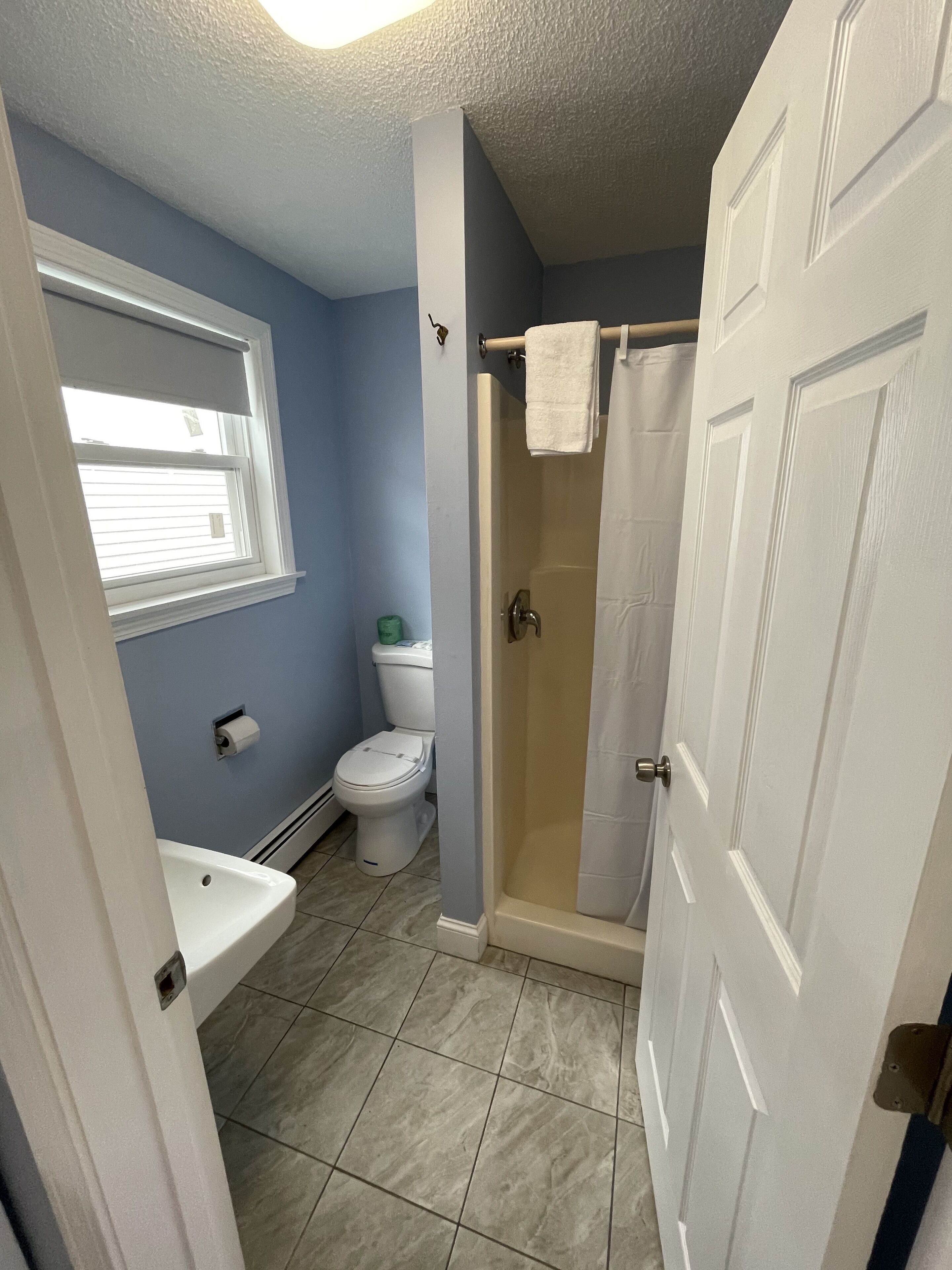 A bathroom with a toilet, sink, and shower.