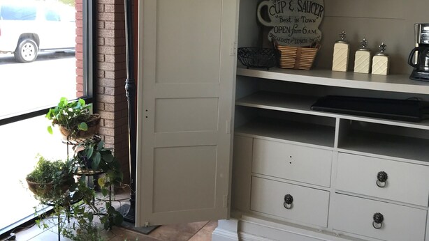 A kitchen area with a sign reading "The Cup & Saucer Best in Town" and a coffee machine. - Pascagoula Extended Stay (Pascagoula)