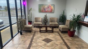 A reception area with a tiled floor, four armchairs, a coffee table, and potted plants. - Pascagoula Extended Stay (Pascagoula)