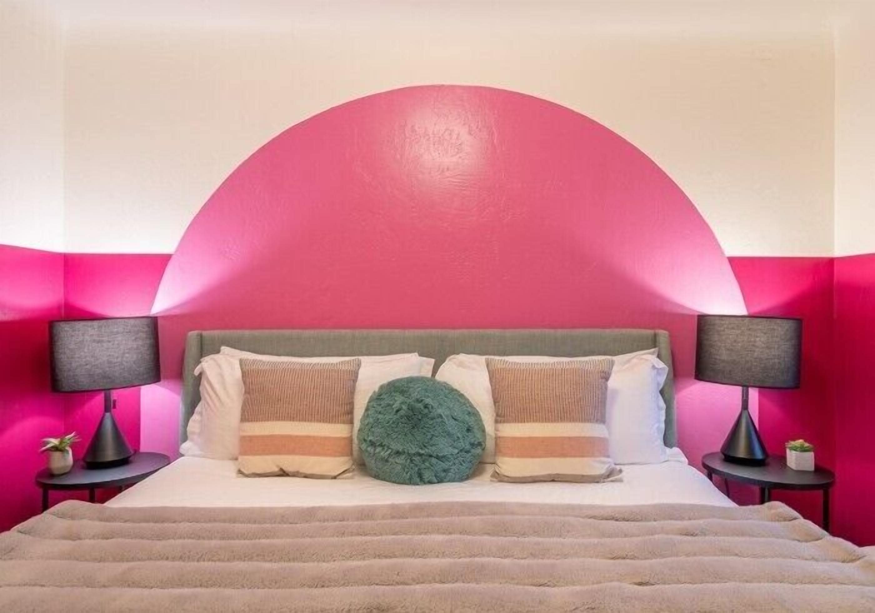 A bed with a headboard, two bedside tables, and a large green pillow.