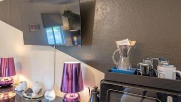 Una cocina moderna con microondas integrado, cafetera y refrigerador pequeño.
