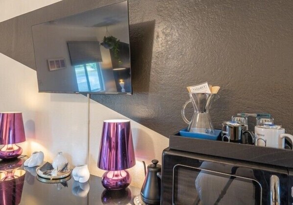 Una cocina moderna con microondas integrado, cafetera y refrigerador pequeño.