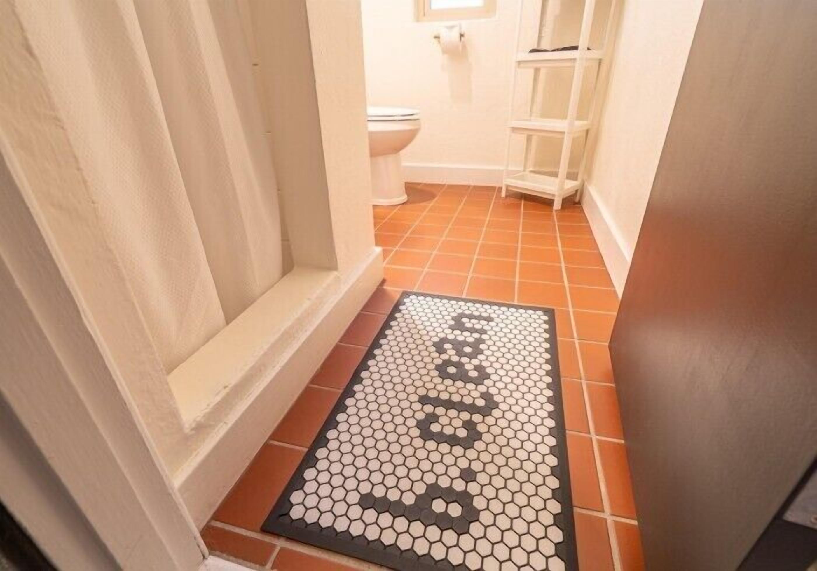 A bathroom with a white toilet, a white sink, and a white shelving unit.