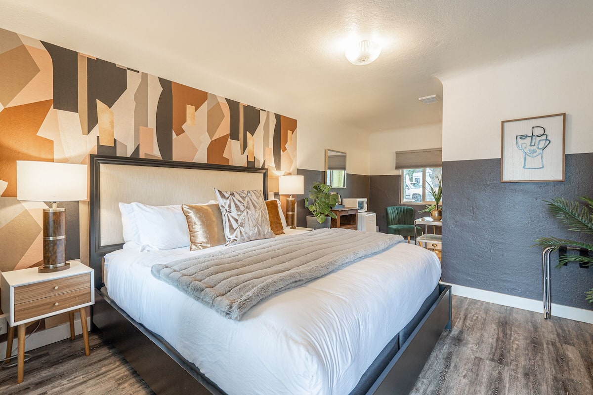 A modern hotel room with a large bed, bedside tables, a desk, and a chair.