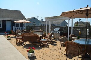 A patio area with wicker furniture, a barbecue grill, and a covered seating area.