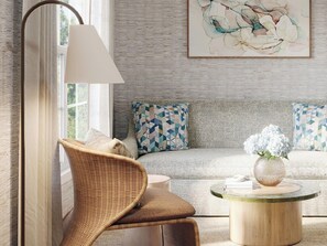 A living room with a wicker chair, a round coffee table, and a sofa with patterned cushions. - Beach Breeze Inn (Falmouth)