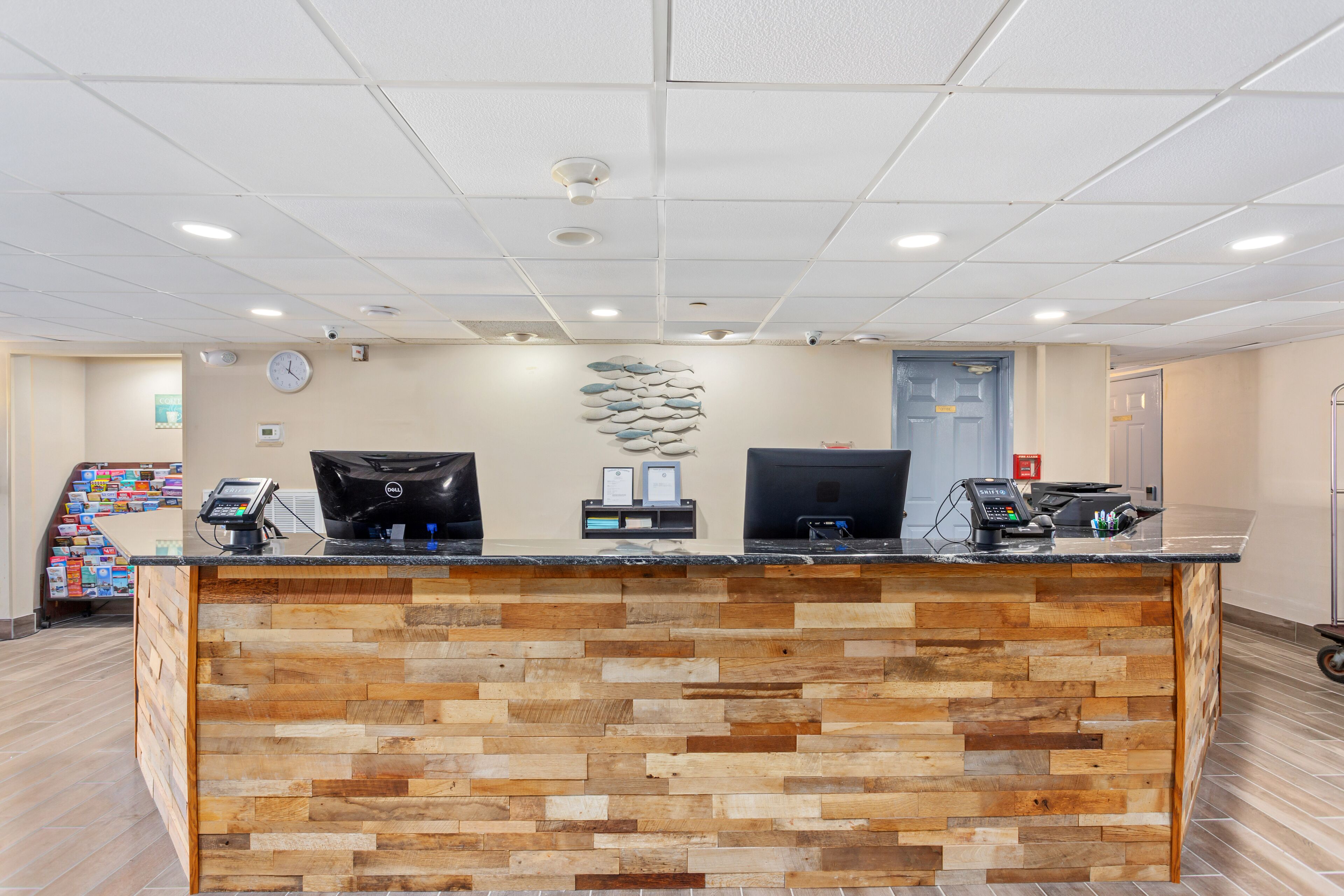 A reception desk with a wooden panel design, two computer monitors, a cash register, and a phone.
