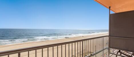 A balcony with a view of the beach and ocean.