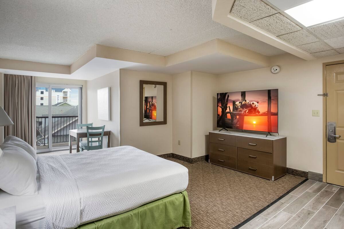 Een hotelkamer met een bed, een televisie, een bureau en een stoel.