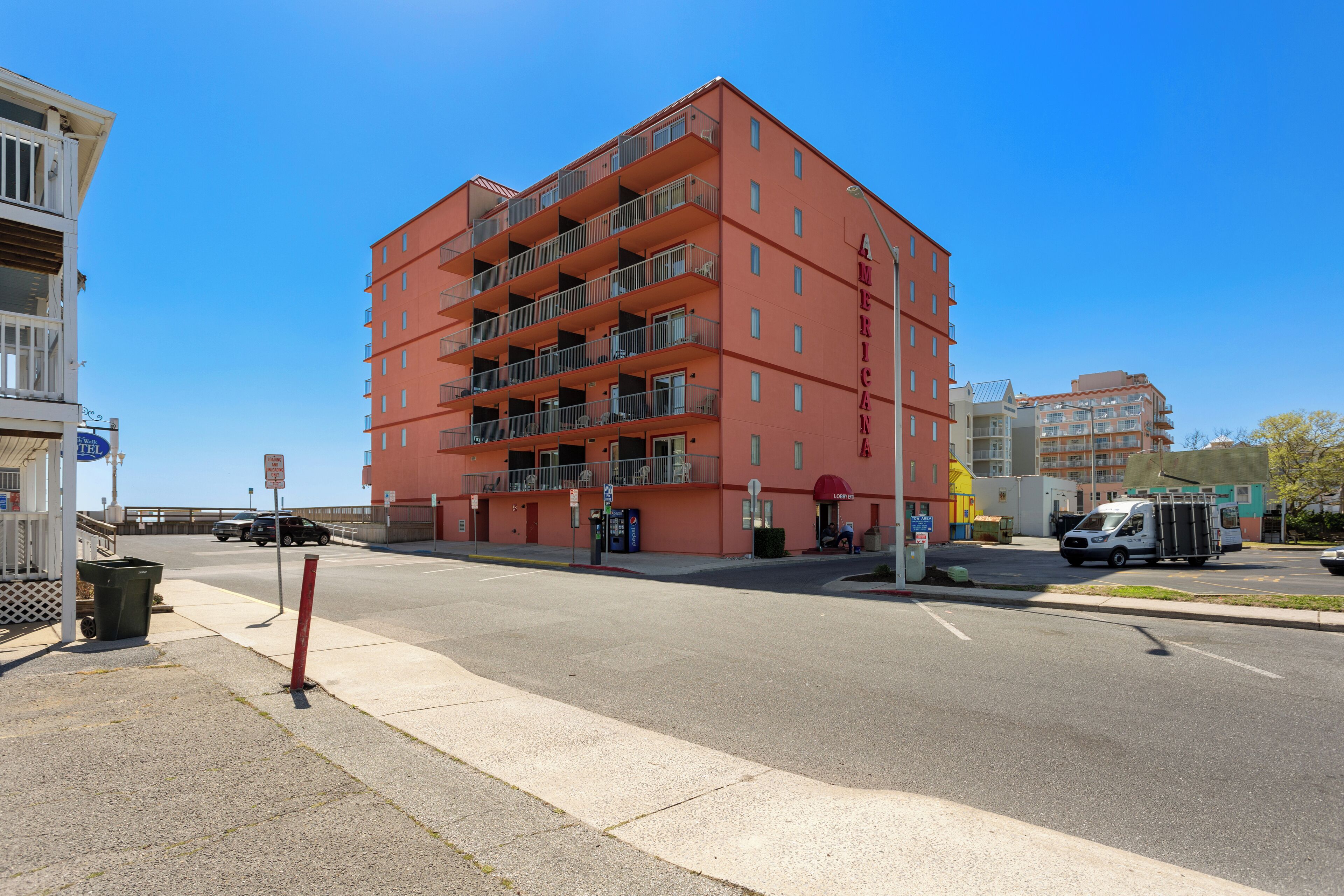 Ein mehrstöckiges Gebäude mit Balkonen, einem Parkplatz und blauem Himmel.