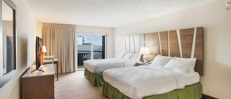 Habitación de hotel con dos camas, un escritorio, una silla, un ventanal con cortinas y vistas al exterior.