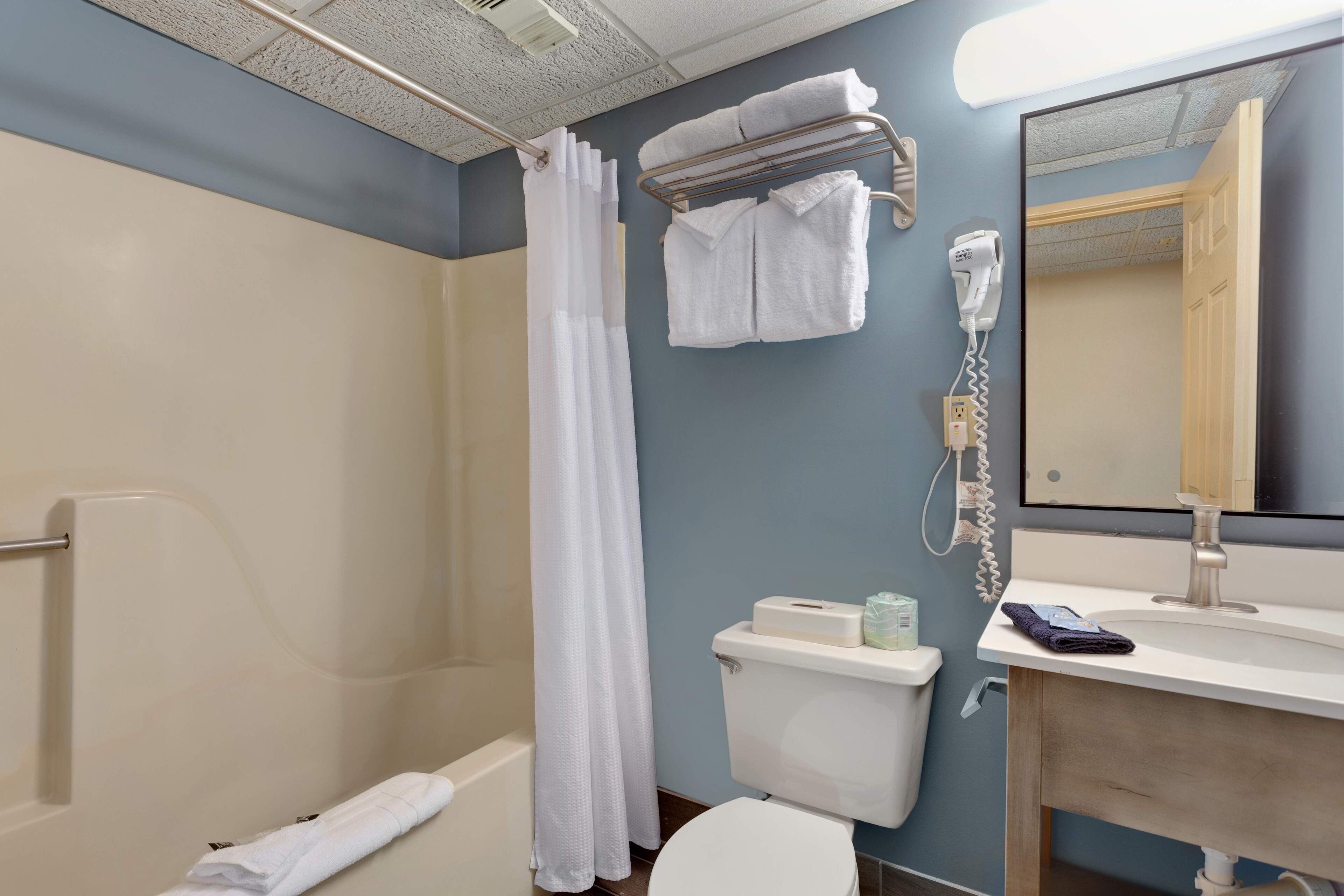A bathroom with a shower, toilet, sink, and a towel rack.