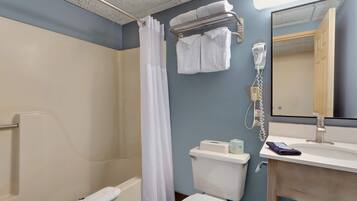 A bathroom with a shower, toilet, sink, and a towel rack.
