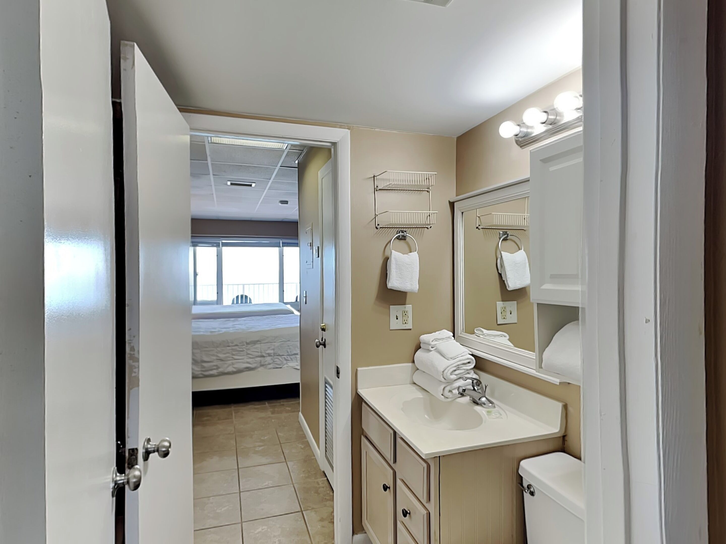 Une salle de bain d’hôtel équipée d’un lavabo, d’un miroir et d’un porte-serviettes.