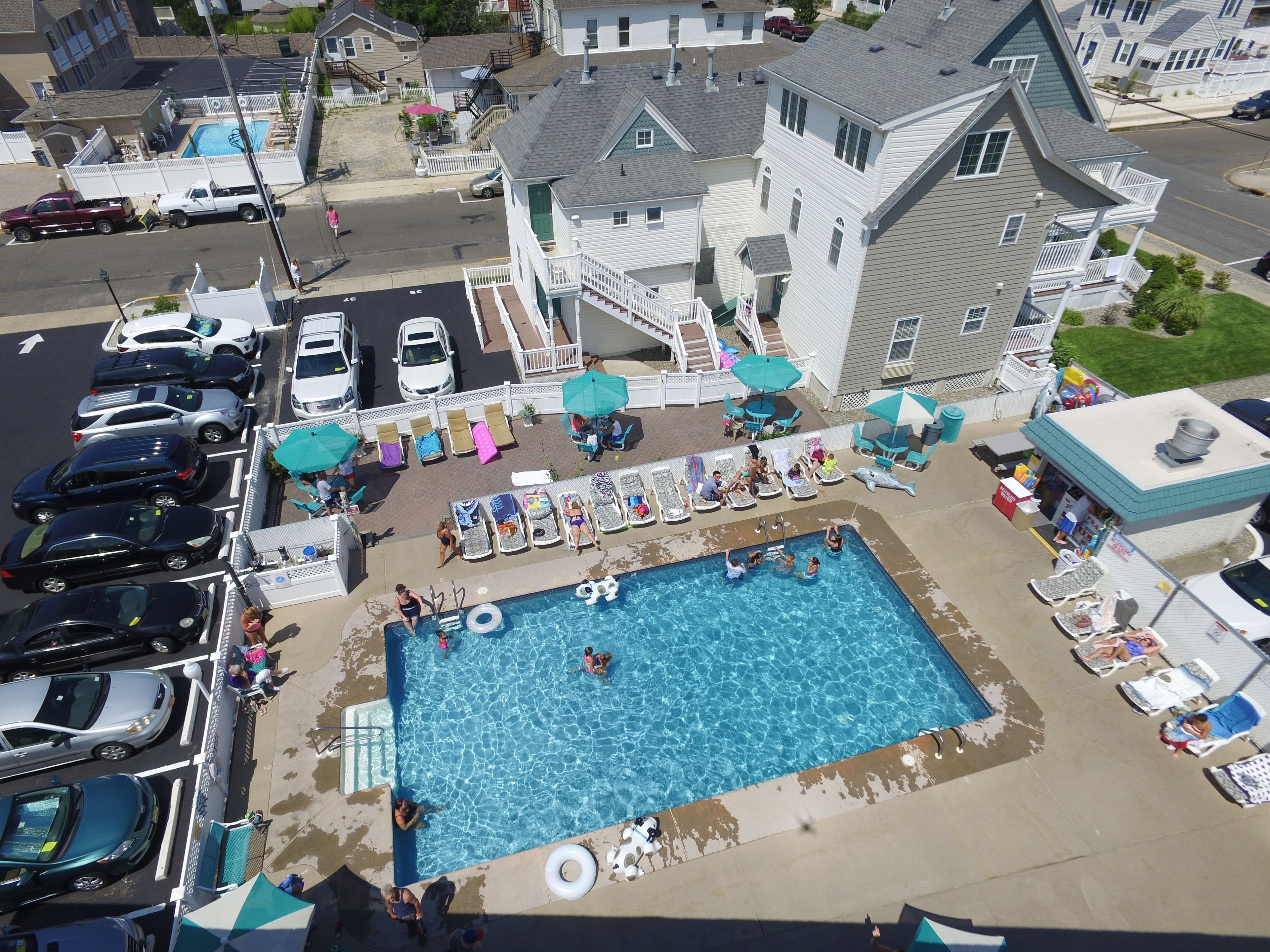 An aerial view of a residential area with a swimming pool surrounded by lounge chairs and umbrellas.