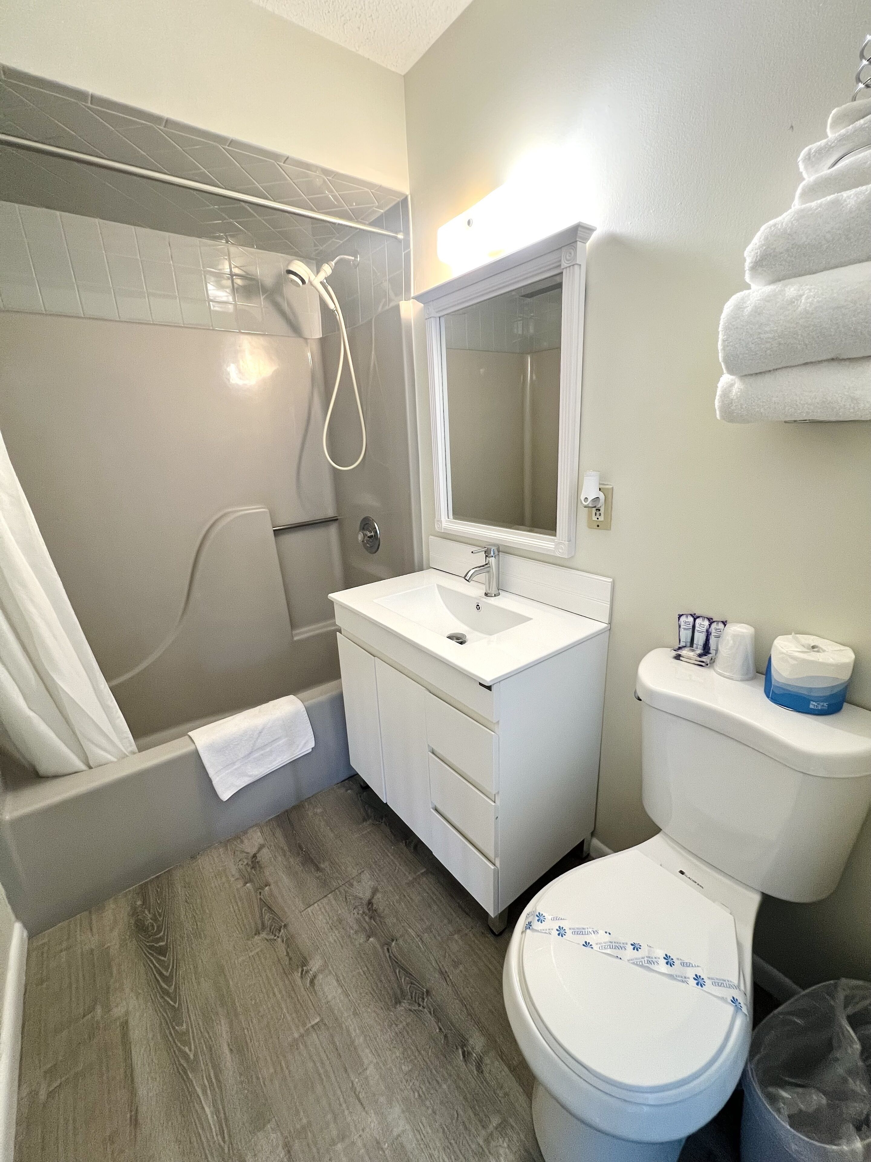 A bathroom with a shower, sink, toilet, and a towel rack.