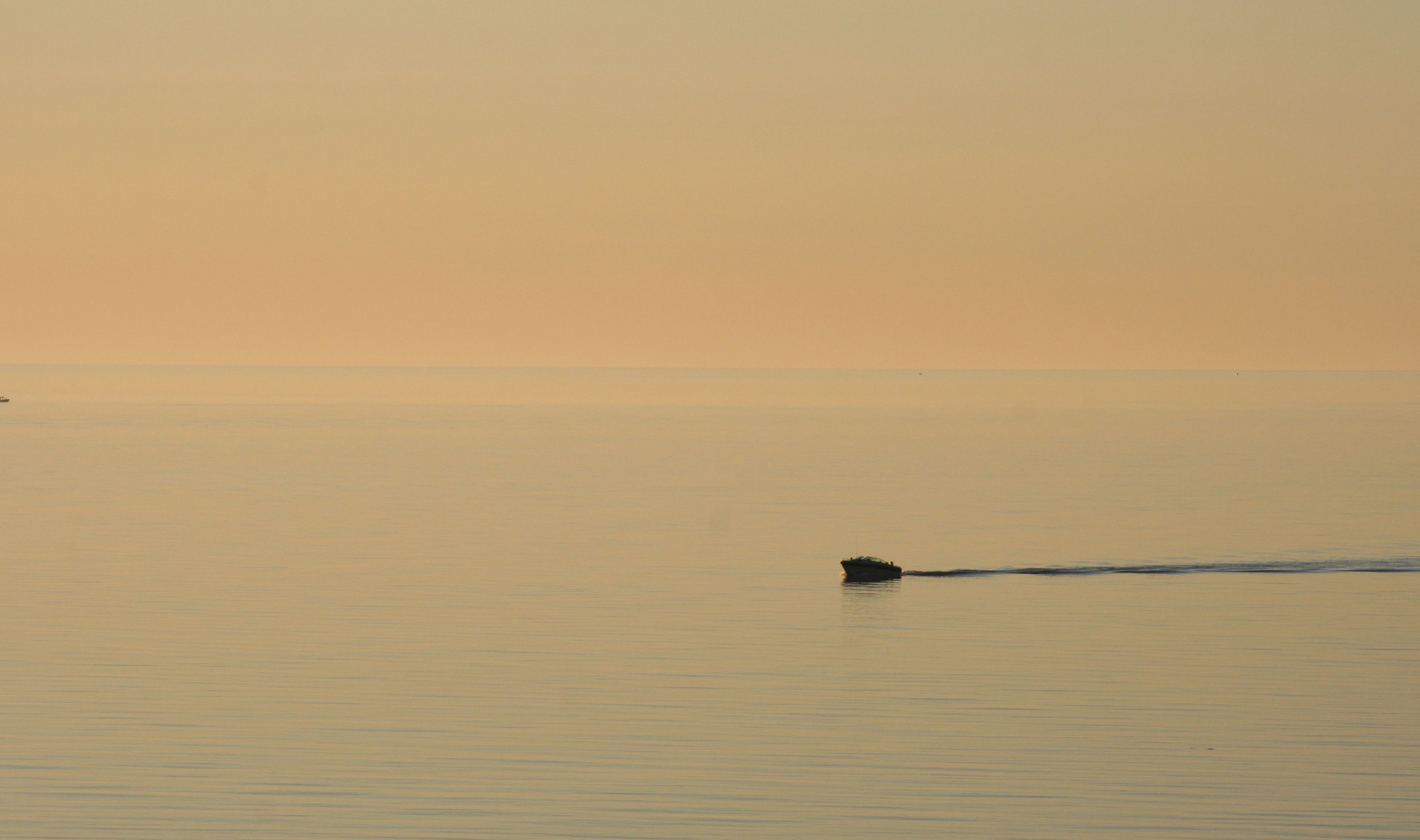 Un mar tranquilo con un pequeño barco a lo lejos.