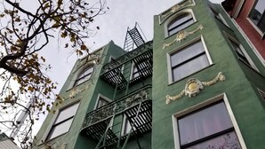 A multi-story building with green facades, ornate window frames, and a fire escape. - Perramont Hotel (San Francisco)