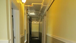 A narrow hallway with patterned carpet, white walls, and a light fixture on the ceiling. - Perramont Hotel (San Francisco)