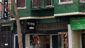 A green building with a 'revamp salon' sign, a 'Perramont Hotel' sign, and a tree in front. - Perramont Hotel (San Francisco)