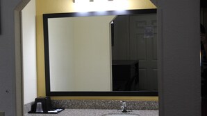 A bathroom with a large mirror, a sink, and a vanity.