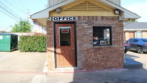 A small brick office building with a sign reading "OFFICE" above the door.