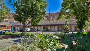 A motel with a row of rooms, a parking area, and a garden with various plants. - Adventure Inn & Motel (Moab)